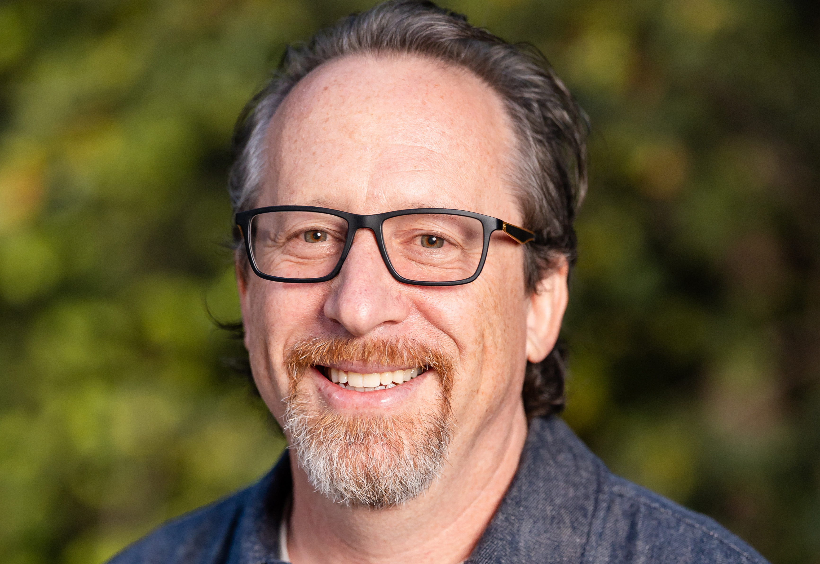 Headshot of smiling man with glasses and a goatee