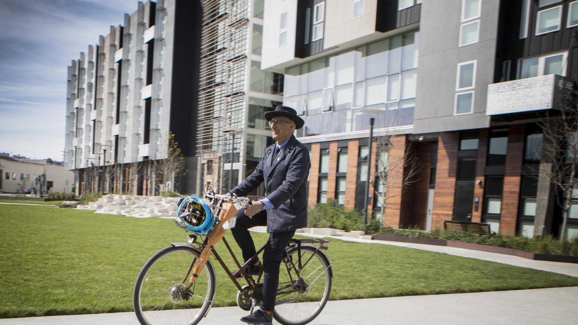 David Baker riding an orange bike on a path in Daggett Plaza at Potero 1010 in San Francisco.