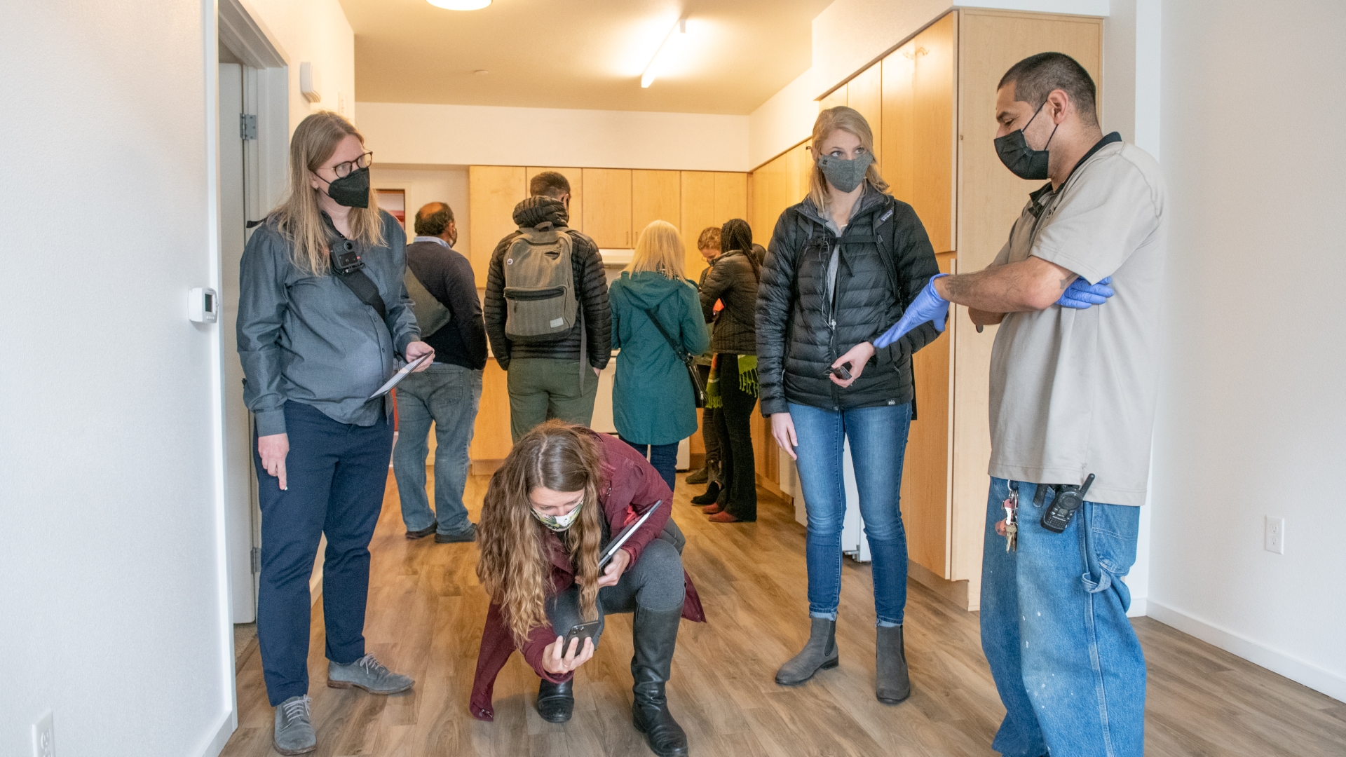 A group of nine people in a building unit, one person crouching down and taking a photo. 