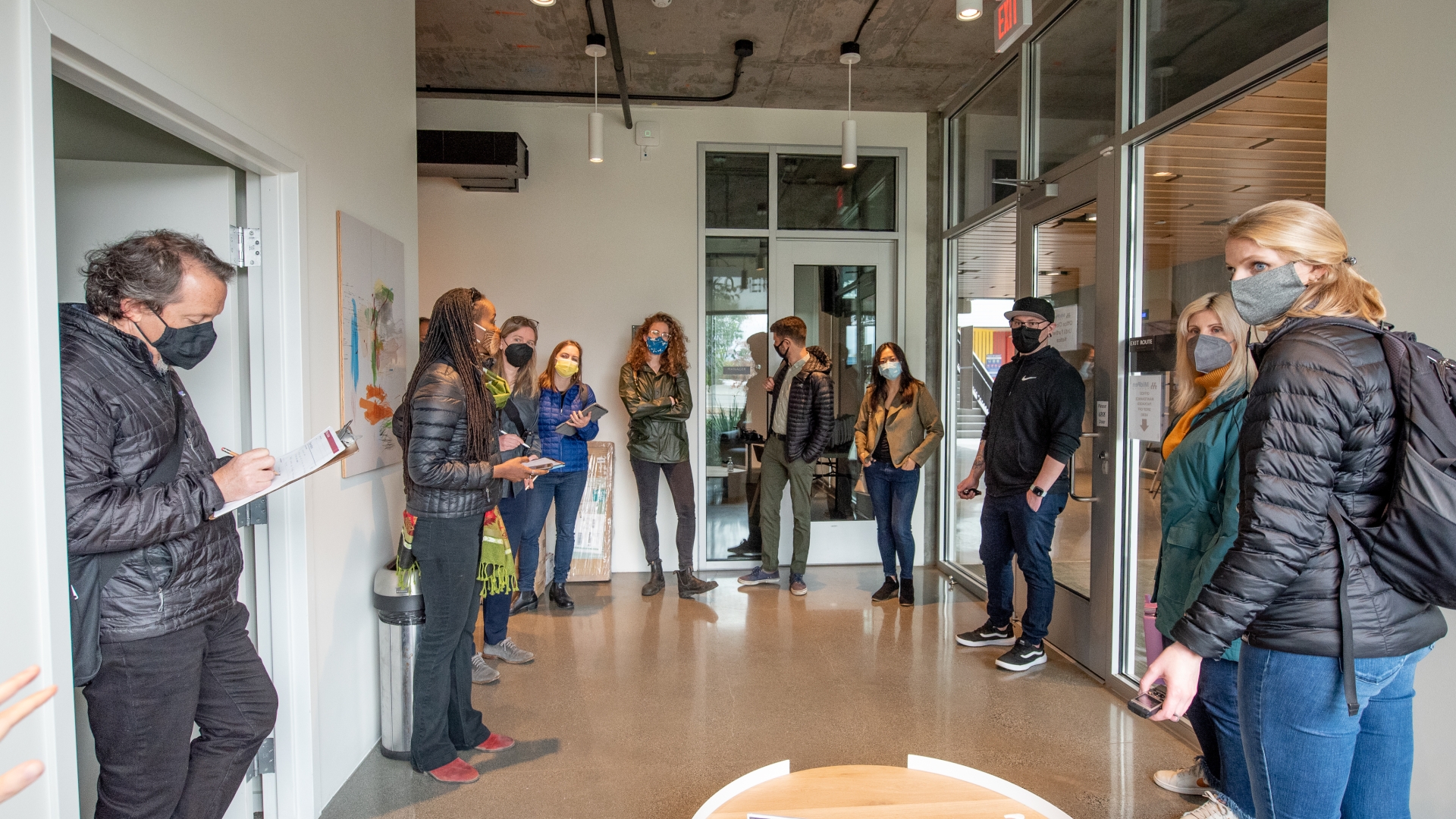 A group of about ten people, standing and taking notes in a community room.