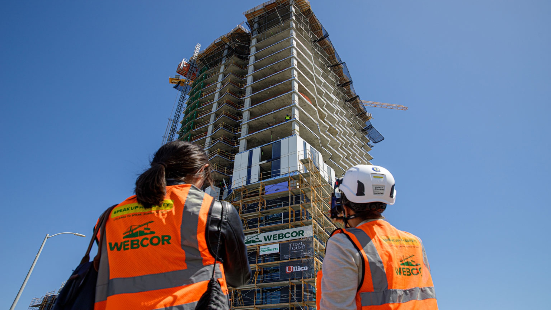 Two people in construction gear looking up to Tidal House SF under construction.