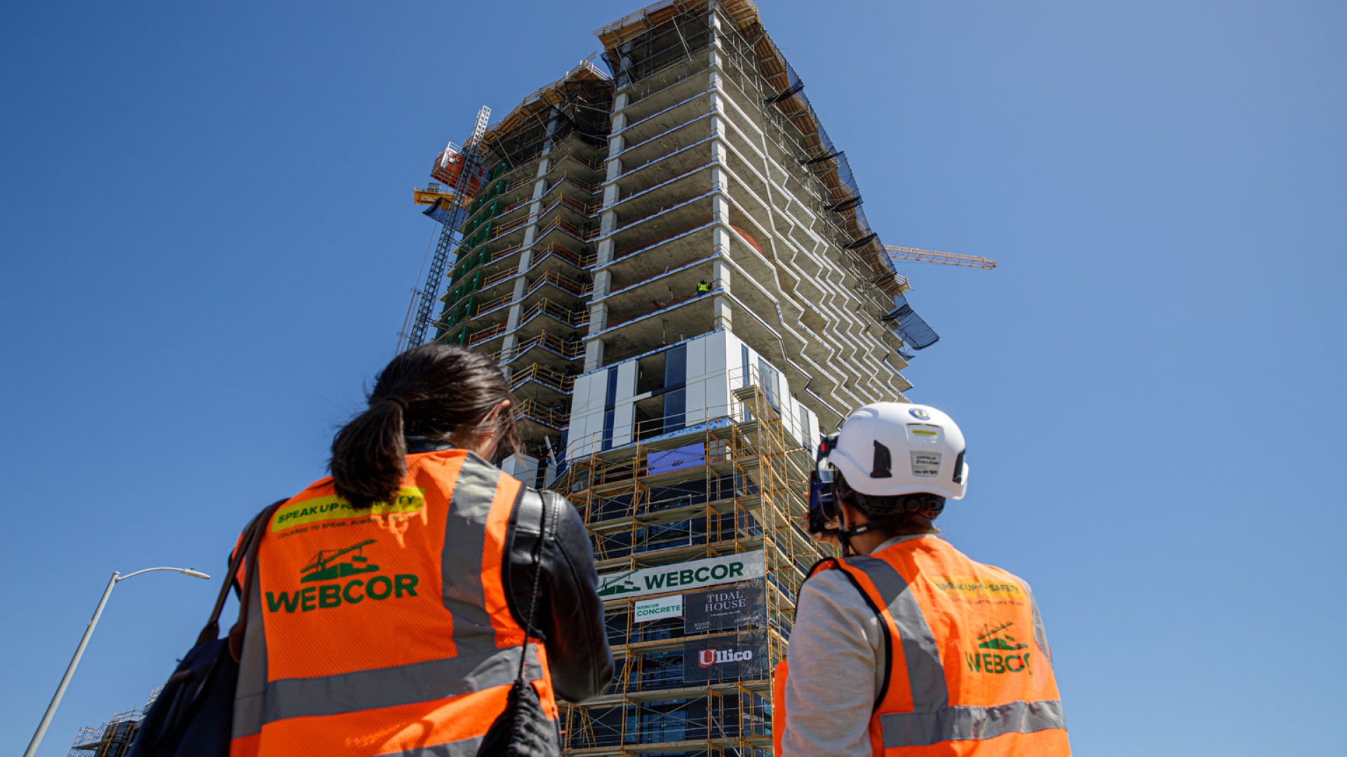 Two people in construction gear looking up to Tidal House SF under construction.