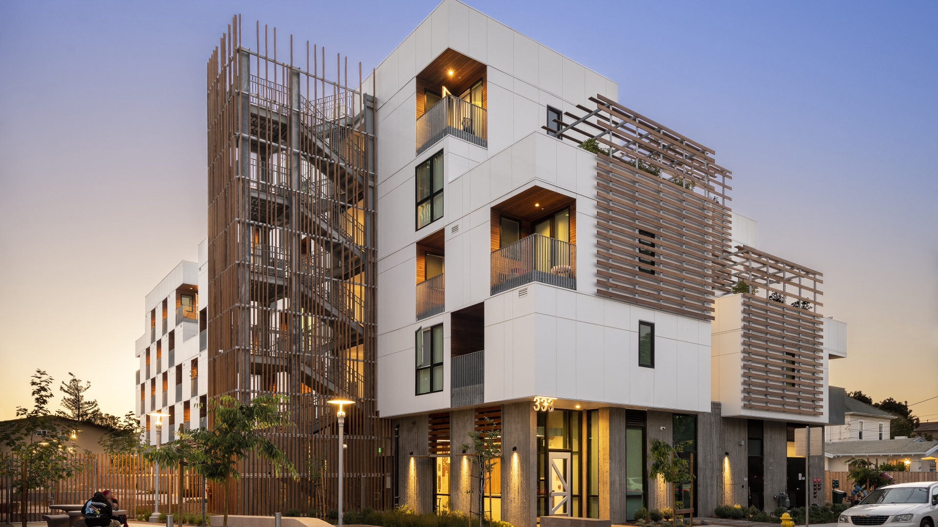 Exterior view of Page Street Studios at dusk with resident windows illuminated in San Jose, California. 