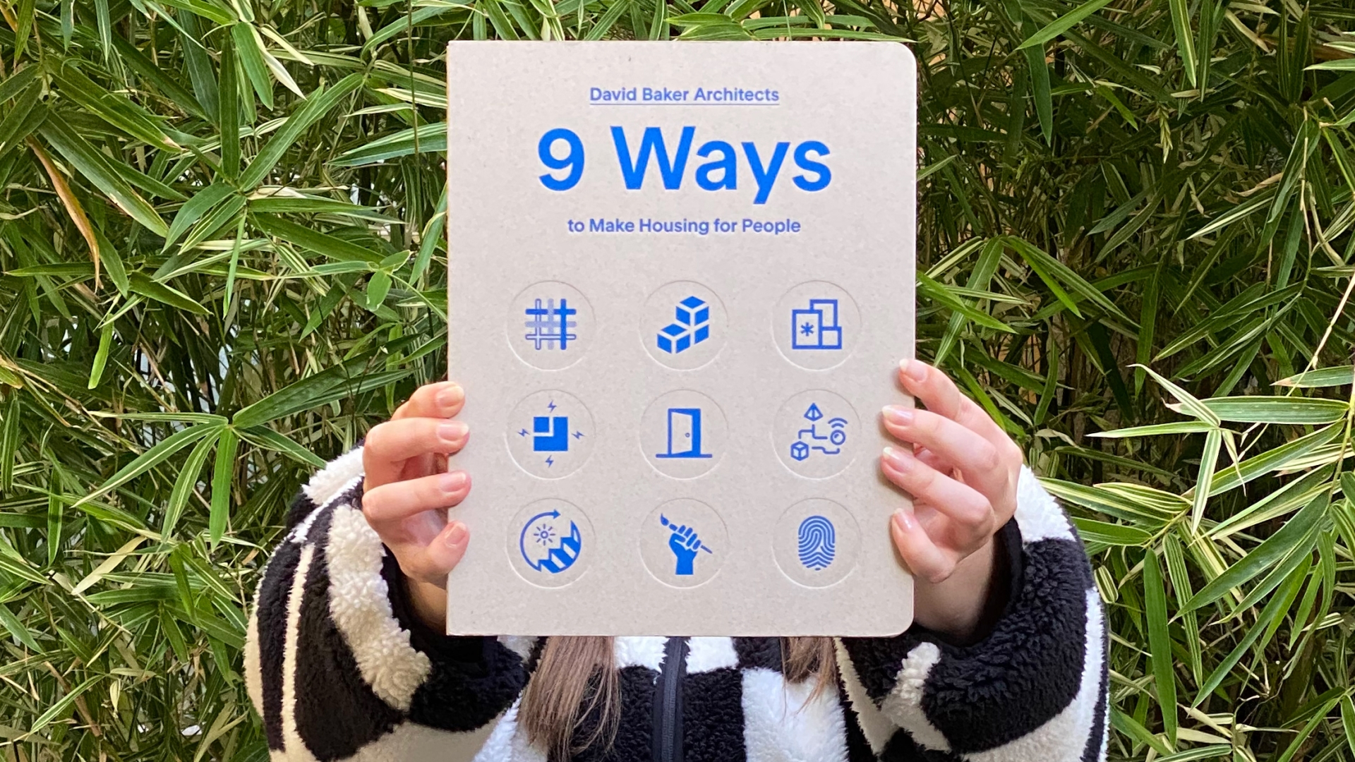 Woman covering her face with "9 Ways to Make Housing for People" 
