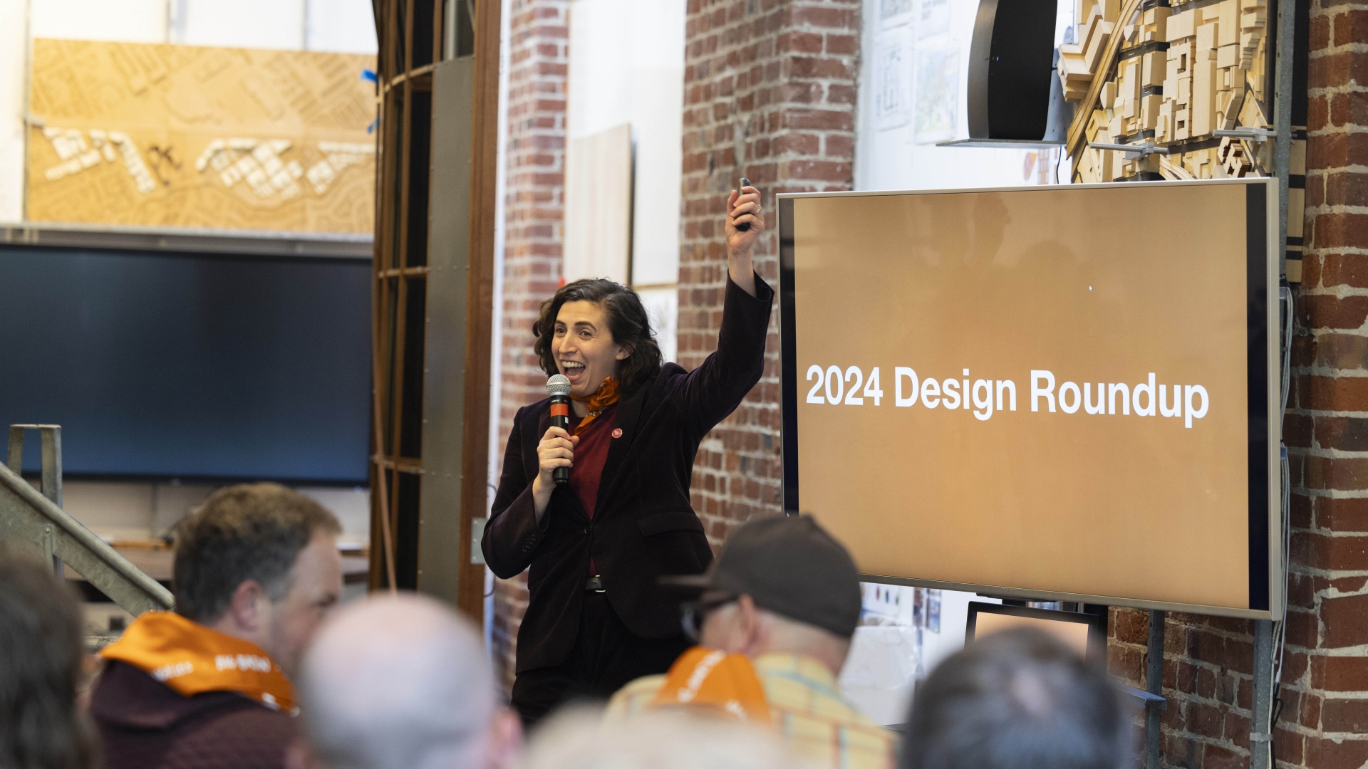 Caroline Souza standing in front of a screen that says "2024 Design Roundup"
