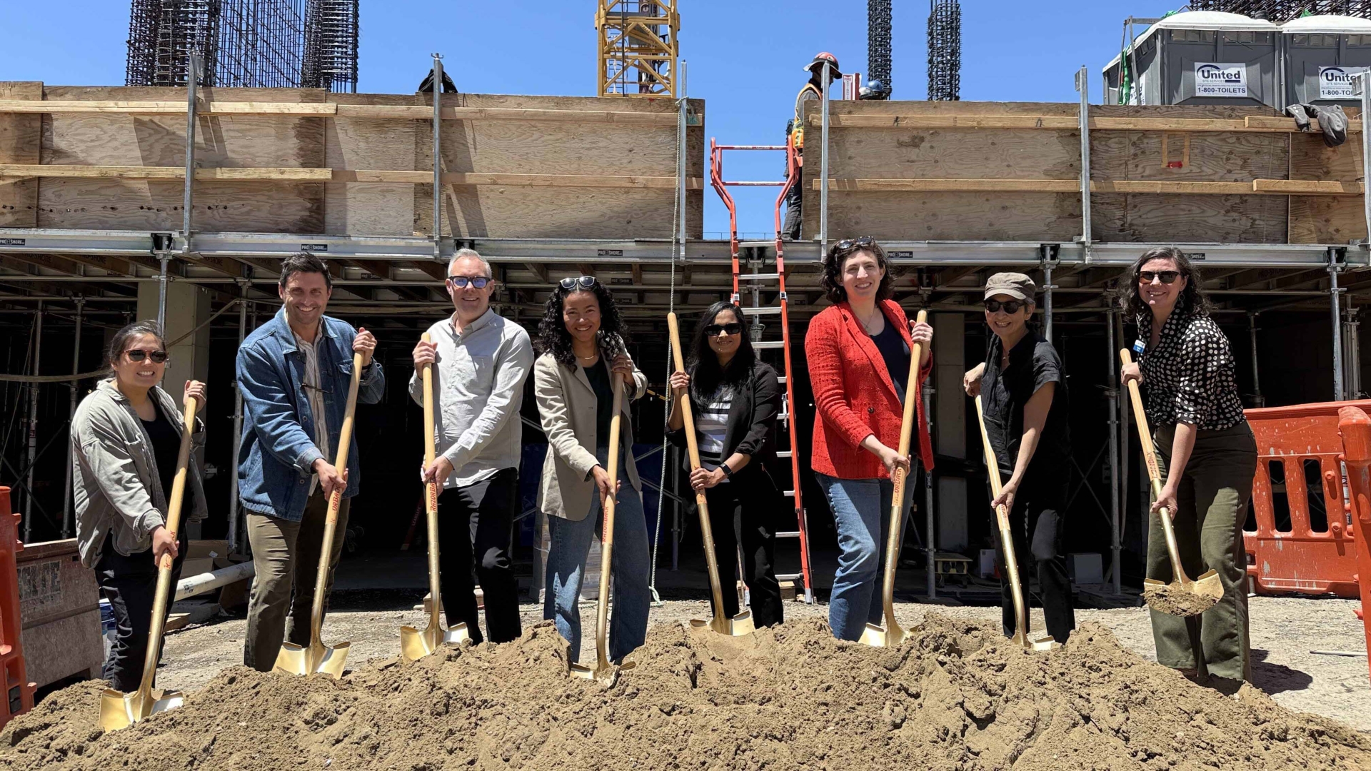 group of people holding shovels at a construction site.