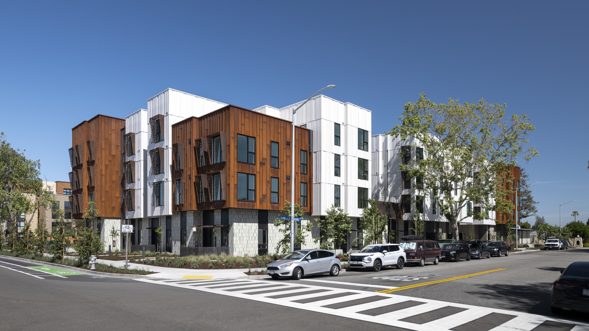Corner view of a modern building with rusted-steel and white volumes. 