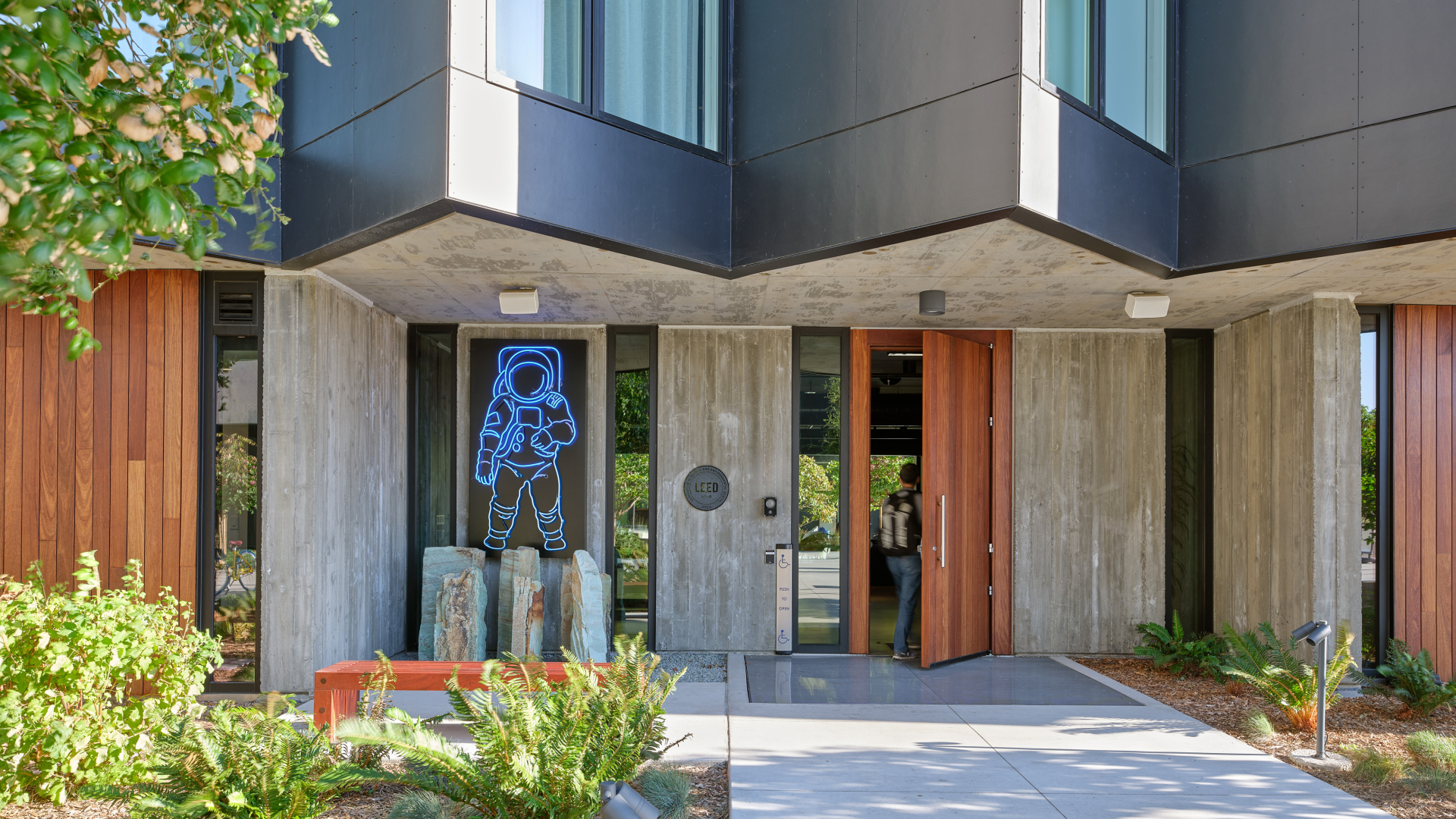 Gray building with man walking through brown wood door