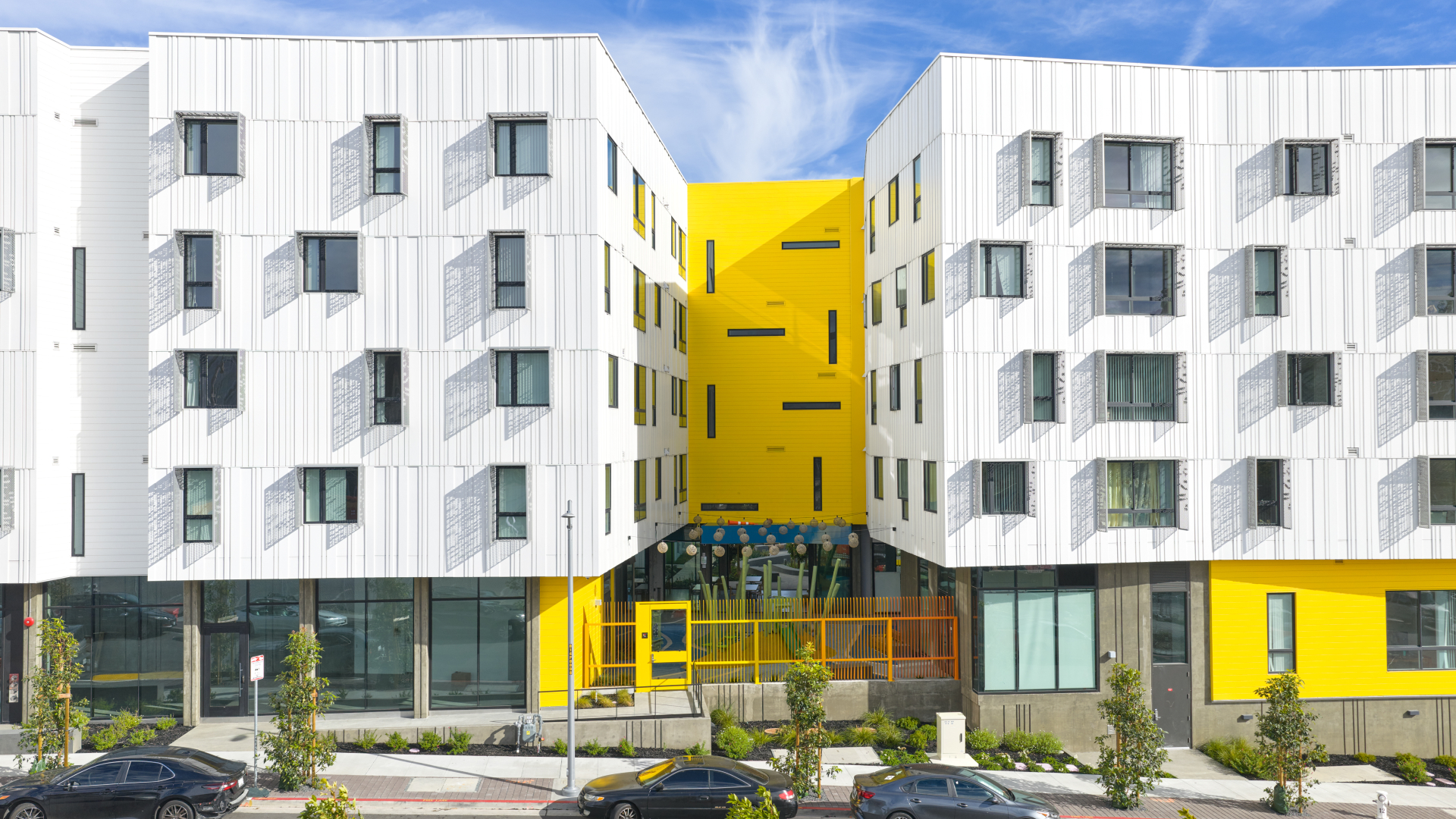 Street view of apartment building and yellow wall with slender windows