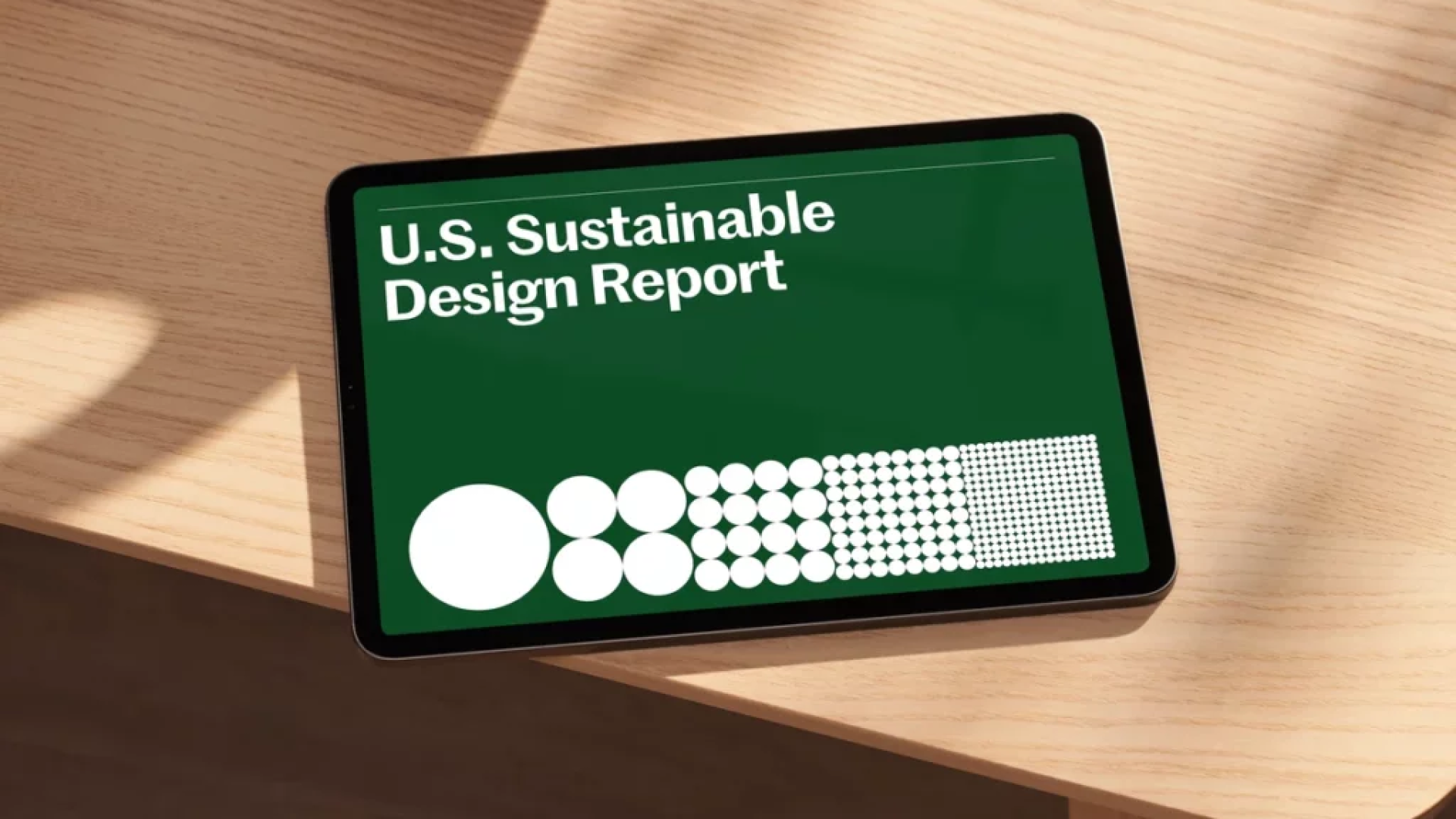 tablet with Sustainable Design Report header lying on a wood table