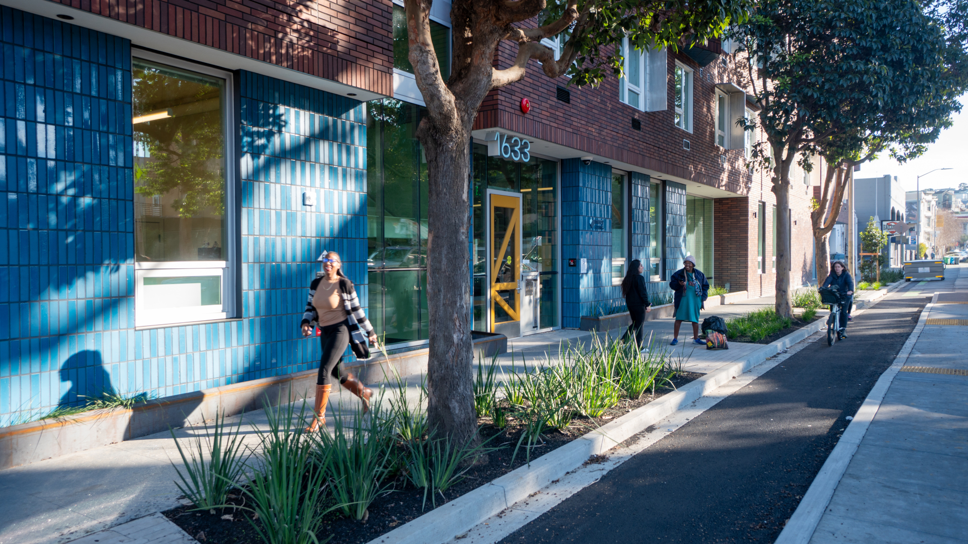 A woman walks by the yellow entry door to a multifamily building