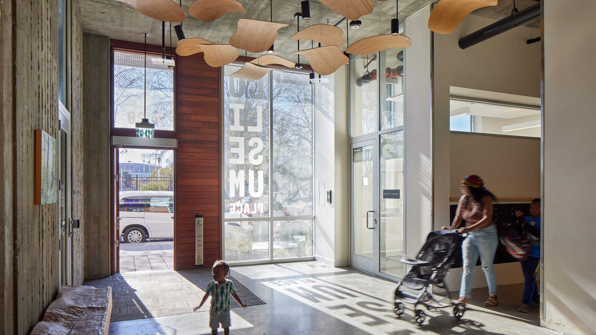 Woman with strolled and toddler walking in lobby of apartment building