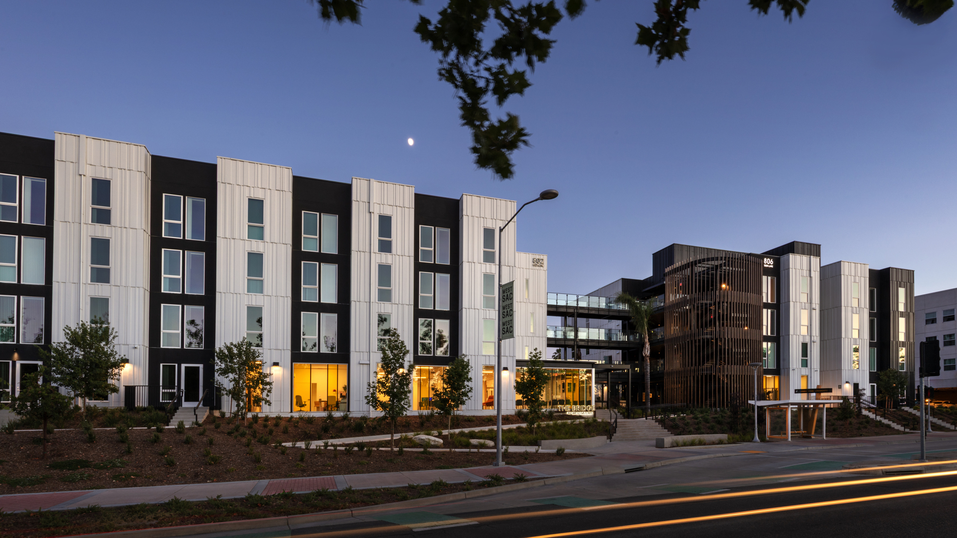 Elevation of multifamily building with black and white vertical bays taken just past dusk
