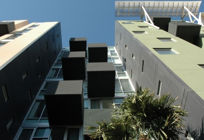 View from street looking up at underside of residential balconies and blue sky. 
