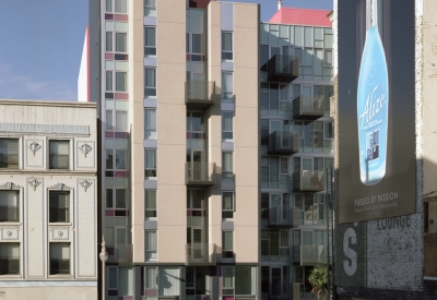 Elevation view of Curran House showing balconies and bright pink accents, with billboards in the foreground.