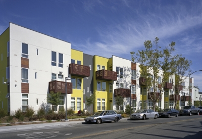 Elevation with wood-slat balconies and a planted sidewalk at Tassafaronga Village in East Oakland, CA. 