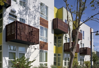 Elevation with wood-slat balconies and a planted sidewalk pathway Tassafaronga Village in East Oakland, CA. . 