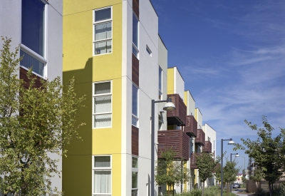 Elevation with wood-slat balconies and a planted sidewalk pathway at Tassafaronga Village in East Oakland, CA. 