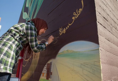 Woman participating in the painting of the large sunflower mural at Station Center Family Housing in Union City, Ca.