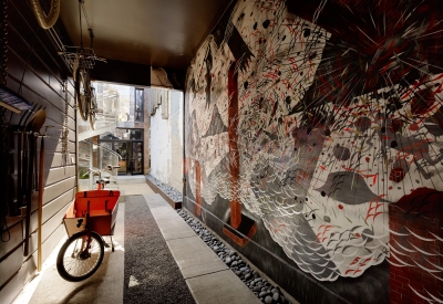 Inside passage to Zero Cottage with a red, white and black mural on the right side of the wall.