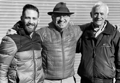 Three men standing with their arms around each other.