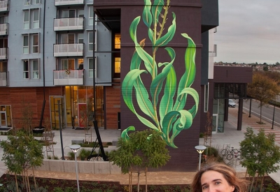 Artist Mona Caron and her in-progress mural at Station Center Family Housing in Union City, Ca.