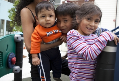 Three children and mom posing on the playground at Paseo Senter in San Jose, California.