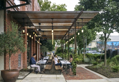 View of people sitting at tables at Bettola Patio underneath the trellis in Birmingham, Alabama.