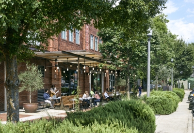 View from the southwest of people sitting at tables at Bettola Patio underneath the trellis in Birmingham, Alabama.