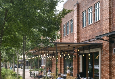 View from the southeast of people sitting at tables at Bettola Patio underneath the trellis in Birmingham, Alabama.