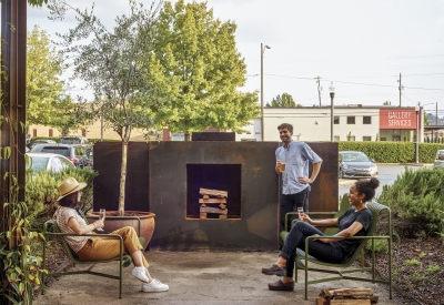 People hanging out at the outdoor steel fireplace at Bettola Restaurant in Birmingham, Alabama.