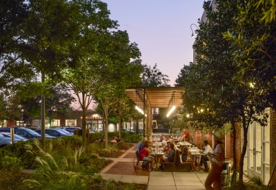 View from the east of people sitting at tables at Bettola Patio underneath the trellis at dusk in Birmingham, Alabama.