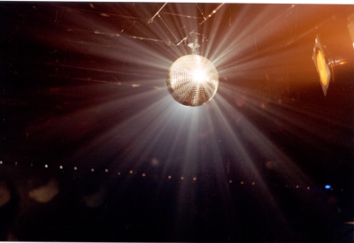 A disco ball hanging and shining in a dark room.