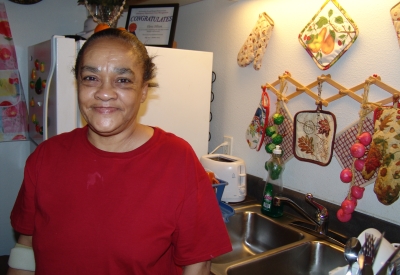 A woman standing in her kitchen at Folsom-Dore Supportive Apartments in San Francisco, California.