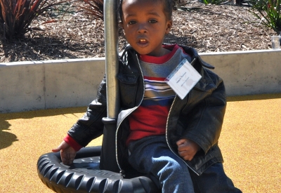 Young boy sitting down in the play area at the grand opening of Ironhorse at Central Station in Oakland, California.