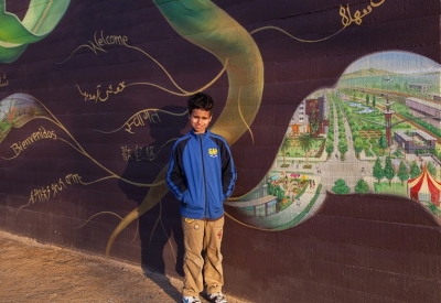 Young boy standing in front of the sunflower mural at Station Center Family Housing in Union City, Ca.