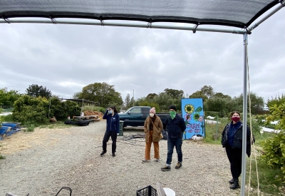 Four people standing visiting the site of the Farm2Market Shade Trellis in Alameda, California.