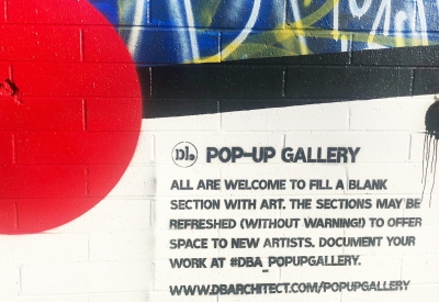 Sign on side of David Baker Architects encouraging artists to fill a blank area with art and to document at #DBA_PopUpGallery.