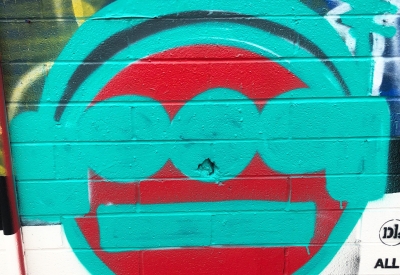 Detail of street art of a red circle with teal design over it.