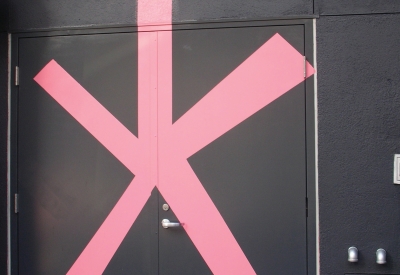 Painted mural on the dark facade of Curran House showing a big pink asterisk with a handwritten legend in yellow reading "Incredible but true"