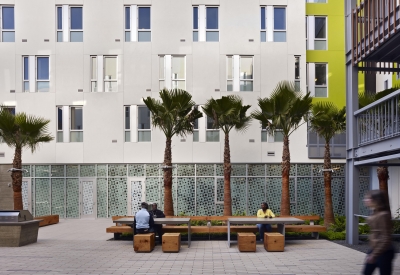 View across Richardson Apartments courtyard showing built-in furniture, palm trees, and privacy screen at on-site clinic.