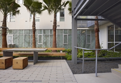 Shady detail of courtyard table and stools with privacy screen of on-site clinic