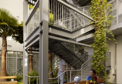 Adult and child sitting on a bench in the courtyard near the open-air stair tower at Richardson Apartments in San Francisco.