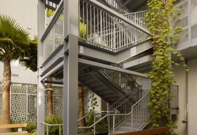 View of bench at base of vine-covered open-air stair tower in Richardson courtyard