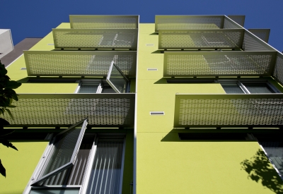 Detail of aluminum sunshades on a white and green wall at Richardson Apartments