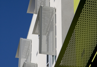 Detail of aluminum sunshades on a white and green wall at Richardson Apartments