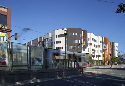 A senior apartment building with a train stop in the foreground, showing proximity to transit. 