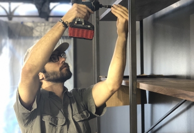 Man with a screwdriver, building a bookshelf at Civic Kitchen in San Francsico.