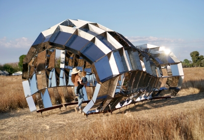 Someone walking through peepSHOW in the desert with mountains behind it in New Cuyama, California.