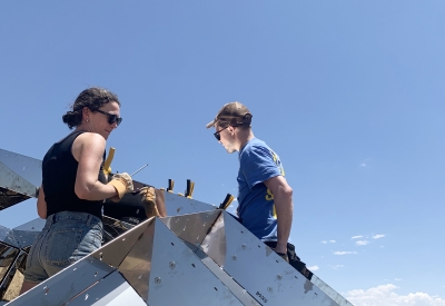 A man and a woman building peepSHOW with blue skies in New Cuyama, California